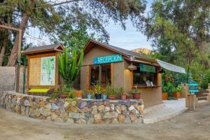 a small restaurant with plants on a stone wall at Cabañas Refugio El Molle in El Molle