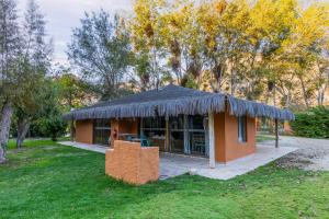 a small building with a thatch roof on the grass at Cabañas Refugio El Molle in El Molle