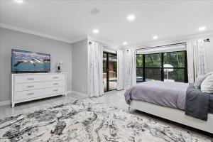 a white bedroom with a bed and a television at Elegant, 4 BDR house with a pool and BBQ in Wellington +51 photos
