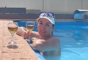a woman holding a glass of wine in a swimming pool at DAR-VIDA Guesthouse in Imsouane