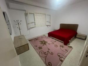 a bedroom with a red bed and a red rug at Les Jasmin Apartment in Menzel Jemil