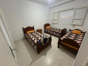 a room with three beds and a window at Les Jasmin Apartment in Menzel Jemil