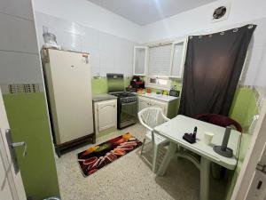 a small kitchen with green and white appliances and a table at Les Jasmin Apartment in Menzel Jemil