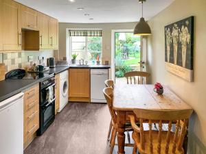 a kitchen with a wooden table and chairs in it at Barters Cottage in Chideock