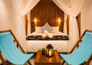 a bedroom with a bed with two blue chairs at CosyBe Villas in Praia do Tofo
