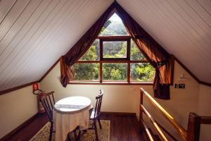a table and chairs in a room with a large window at Pousada Highland in Santo Antônio do Pinhal