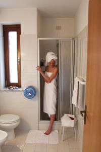 Una mujer parada en una ducha en un baño en Hotel Garni Ongaro, en Selva di Cadore