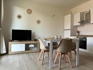 a kitchen with a table with chairs and a television at La Curt by Ambroeus apartments in Inzago