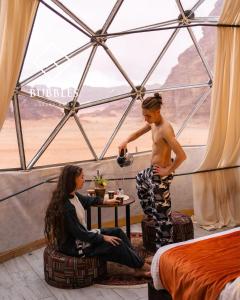 a man standing in a tent with a woman at BUBBLES LUXURY CAMp in Wadi Rum