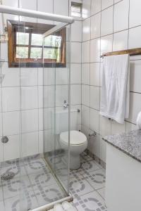 a bathroom with a toilet and a glass shower door at Hospedaria Os Memorialistas - Paranapiacaba in Paranapiacaba