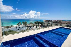 a swimming pool with the ocean in the background at Depa MAJUM Playa del Carmen in Playa del Carmen