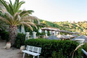 a white bench in front of a building with a palm tree at Stromboli Beach Tropea in Santa Domenica