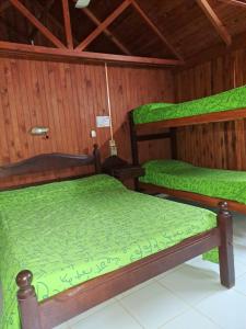 two bunk beds in a room with green sheets at Las Cabañas in Santo Tomé