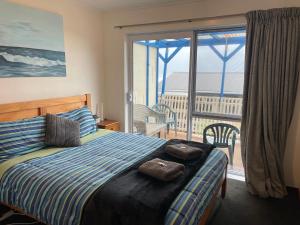 a bedroom with a bed with a view of a balcony at Punakaiki Beach Hostel in Punakaiki