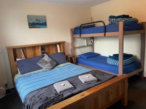 a bedroom with a bunk bed with blue sheets at Punakaiki Beach Hostel in Punakaiki +27 photos