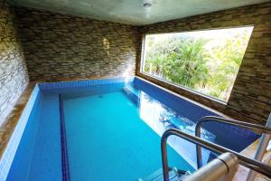 a swimming pool in a room with a window at Pousada Highland in Santo Antônio do Pinhal