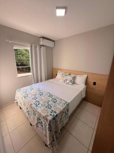 a bedroom with a bed with a floral bedspread and a window at Season Ilhéus in Ilhéus +36 photos