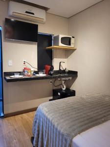 a room with a bed and a kitchen with a microwave at Studio Moderno e Prático Wi-Fi Rápido e AC in Ribeirão Preto +24 photos
