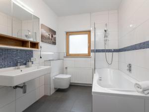 a white bathroom with a sink and a tub and a toilet at Dorf30 in Going am Wilden Kaiser +32 photos