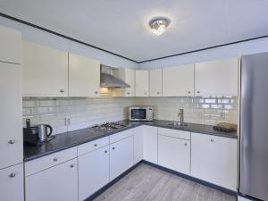 a white kitchen with white cabinets and a refrigerator at t Kaatsheuveltje 1 in Kaatsheuvel