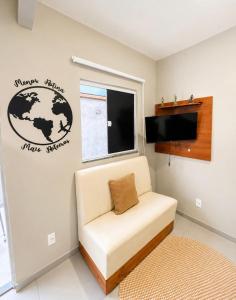 a living room with a white couch and a tv at Maria Lofts in Itaguaí