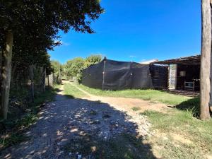 a dirt road with a fence next to a house at Hospedaje El Rancho in Castillos
