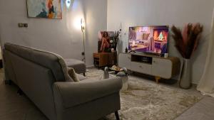 a living room with two chairs and a flat screen tv at Le Cocon de Jade - Nylon Bastos in Yaoundé