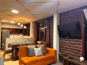 a living room with a couch and a tv on a brick wall at Relax Home in Puyo
