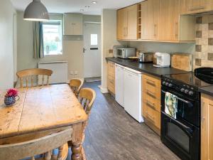 a kitchen with a wooden table and a dining room at Barters Cottage in Chideock