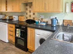 a kitchen with a washing machine and a sink at Barters Cottage in Chideock