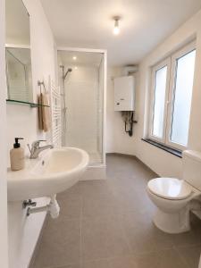 a white bathroom with a sink and a toilet at Maison de Florence in Brussels