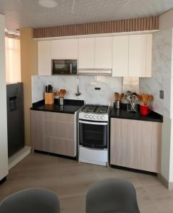 a kitchen with white cabinets and a stove top oven at APART SExTA ESTACIÓN in Juliaca