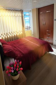 a bedroom with a red bed with a vase of flowers at APART SExTA ESTACIÓN in Juliaca