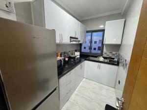 a kitchen with white cabinets and a stainless steel refrigerator at Alhoceima - vue sur la mer- Green village2 in Al Hoceïma