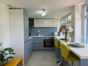 a kitchen with blue and white cabinets and yellow chairs at Ottov Raj Na Dunavu in Krčedin