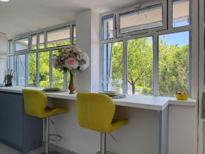 a kitchen with a counter with yellow chairs and windows at Ottov Raj Na Dunavu in Krčedin