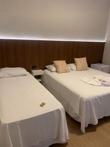 two beds sitting next to each other in a room at Hotel Iaguara in Coxim