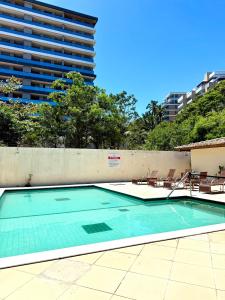 a swimming pool with chairs and a tall building at Season Ilhéus in Ilhéus