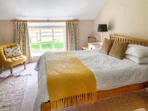 a bedroom with a bed and a chair and a window at Barters Cottage in Chideock