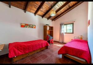 two beds in a room with red sheets at Cabañas Siddharta in Los Reartes