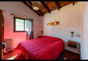 a bedroom with a red bed and a window at Cabañas Siddharta in Los Reartes