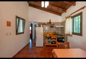 a kitchen with a white refrigerator and a table at Cabañas Siddharta in Los Reartes +5 photos