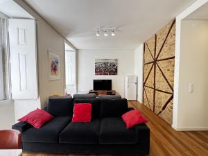 a living room with a black couch with red pillows at Lux Old Town in Lisbon