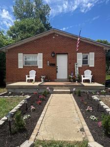 a brick house with two chairs and an american flag at Homestead Bungalow in Dayton