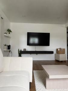 a living room with a white couch and a flat screen tv at Homestead Bungalow in Dayton