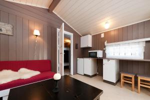 a living room with a red couch and a kitchen at Sæteråsen Hytter & Camping Trysil in Trysil +87 photos
