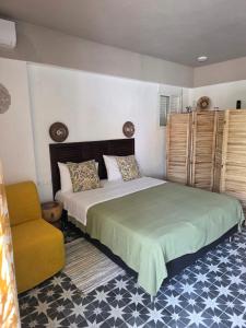 a bedroom with a large bed and a yellow chair at Levanta apartment in Asprovalta