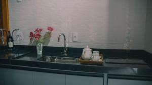 a kitchen sink with a vase of flowers on a counter at Chalés Florenzza in Santa Teresa