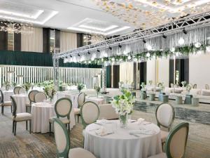 a banquet hall with white tables and chairs at Mövenpick Hotel Waad Al Shamal in Ţurayf