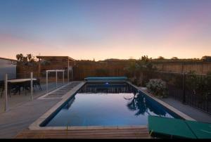 a swimming pool in a backyard with a table at Character Villa Oasis - Pool & Beach in Athenree
